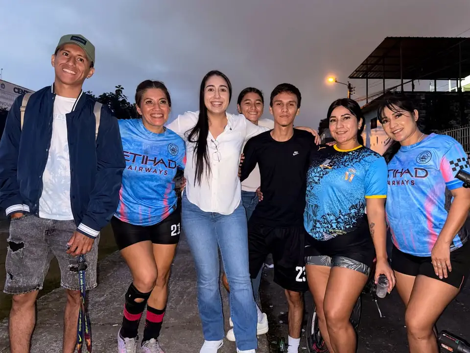 Grupo de deportistas y asistentes posa junto a la autora en una cancha.
