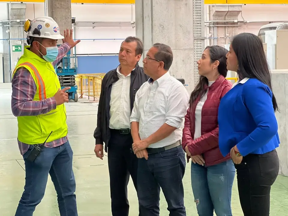Un grupo escucha a un trabajador con casco y chaleco dentro de una instalación ferroviaria.