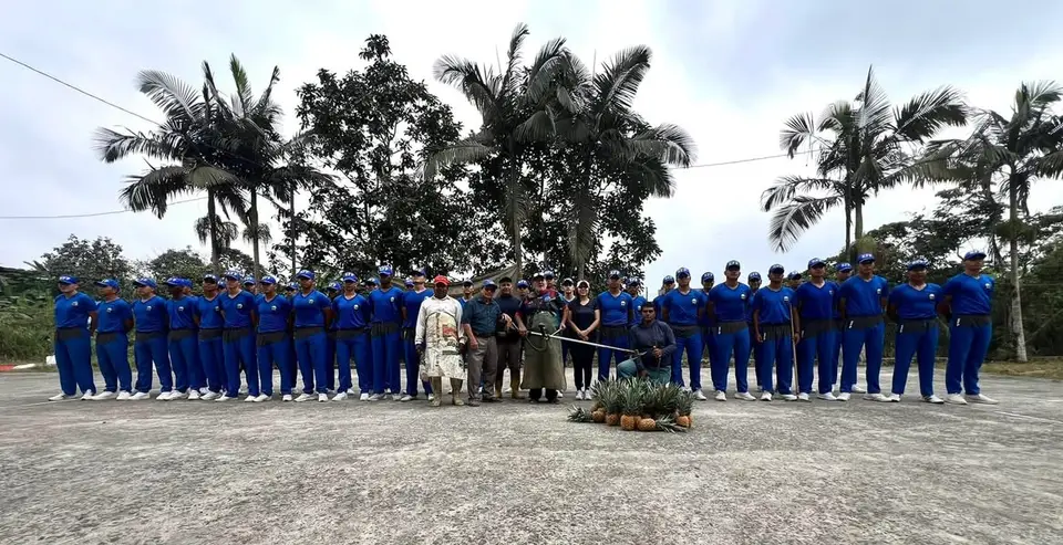Grupo numeroso de personas con camisetas y gorras azules posa en un espacio exterior.