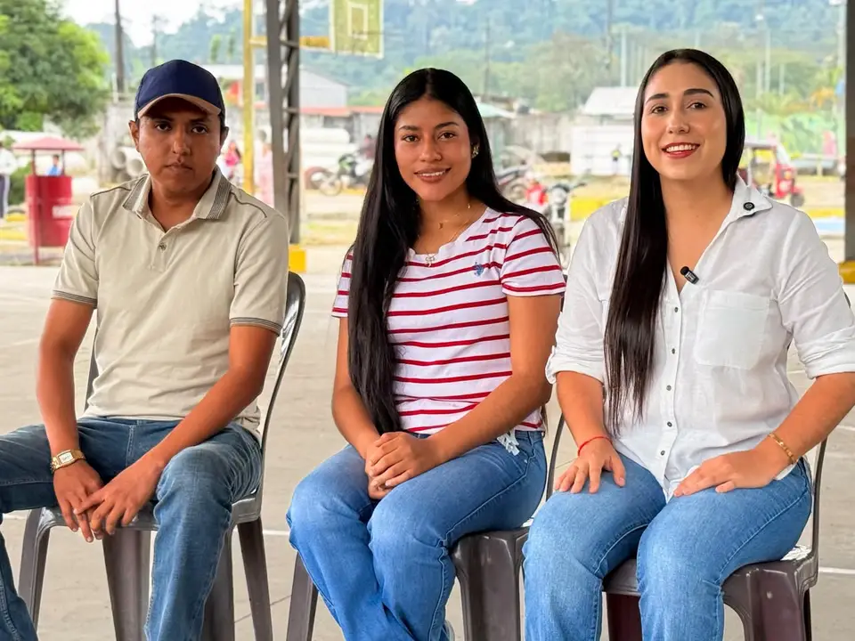 Tres personas sentadas en un espacio comunitario durante una conversación.