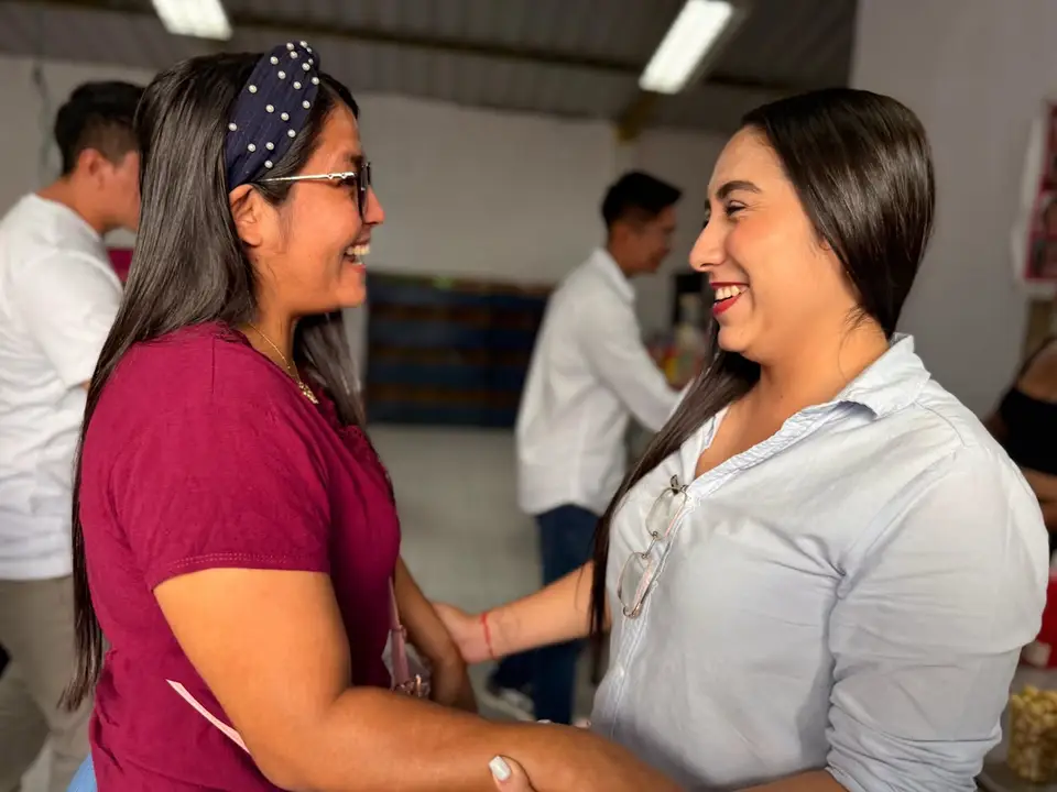 Liliana Silva conversa con una mujer adulta en un salón de talleres.