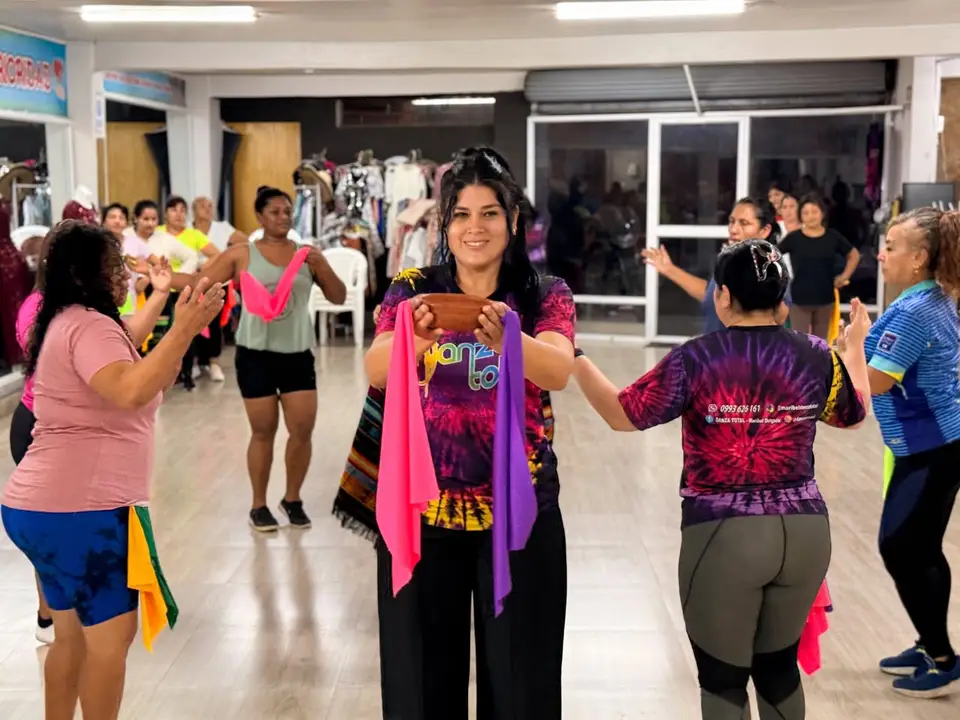 Participantes de un grupo de danza posan juntas en un espacio interior.
