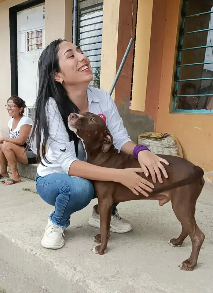 Liliana acaricia un perro grande marrón en el exterior de una vivienda.