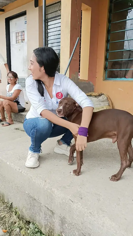 Liliana abraza a un perro marrón junto a una vivienda.