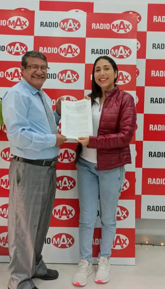 Liliana y un hombre sostienen un documento frente a un fondo con logotipos de una radio.