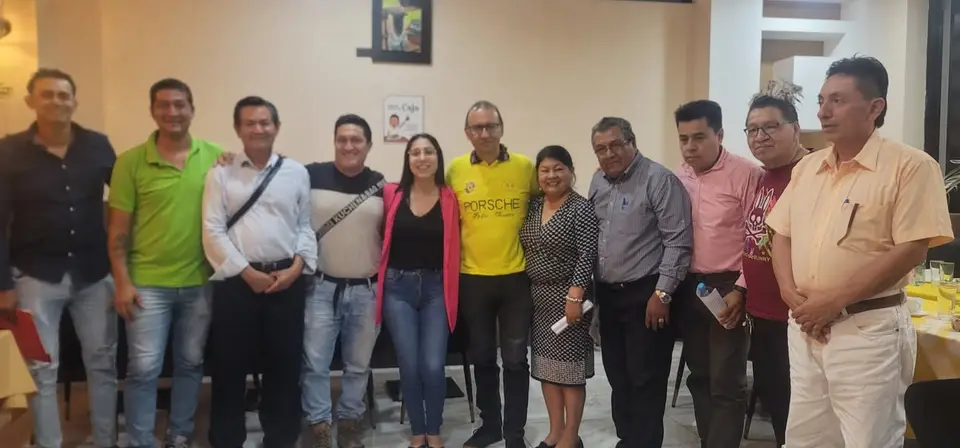 Grupo de personas adultas posa en el interior de un local; la autora aparece entre ellos.