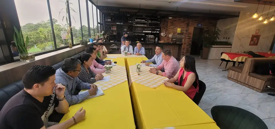 Personas adultas participan en una reunión dentro de un local.