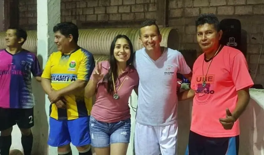 Liliana Silva junto a integrantes adultos de un equipo deportivo durante una actividad nocturna.