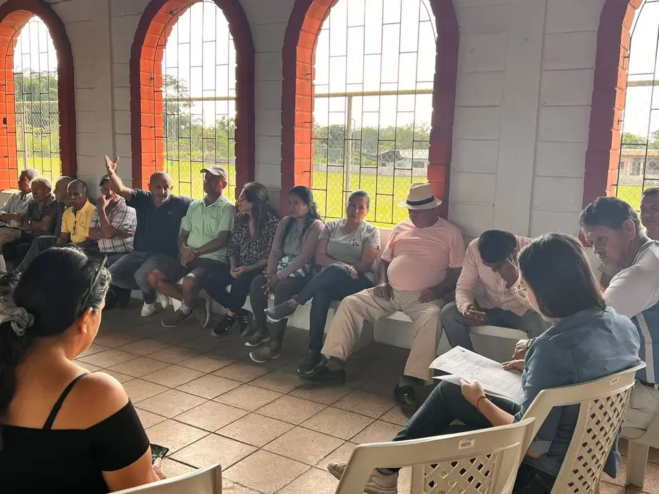 Liliana Silva conversa con personas adultas durante una reunión comunitaria en La Aurora.